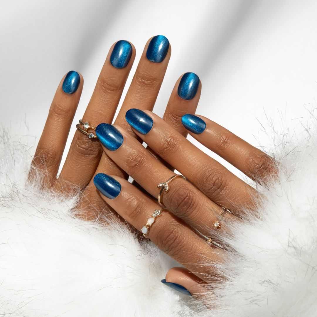 imPRESS Color FX - Reconnect, glanzende blauwe nagels met een elegante vorm, omringd door sieraden en een zachte witte stof.