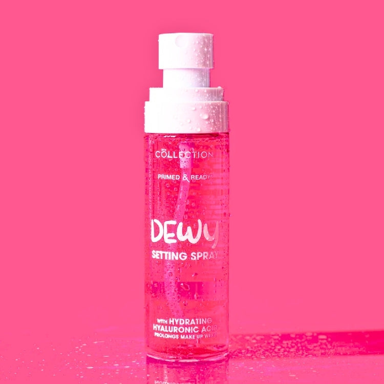 Primed & Ready Dewy Setting Spray in een transparante fles met roze vloeistof en een vernevelspuit.